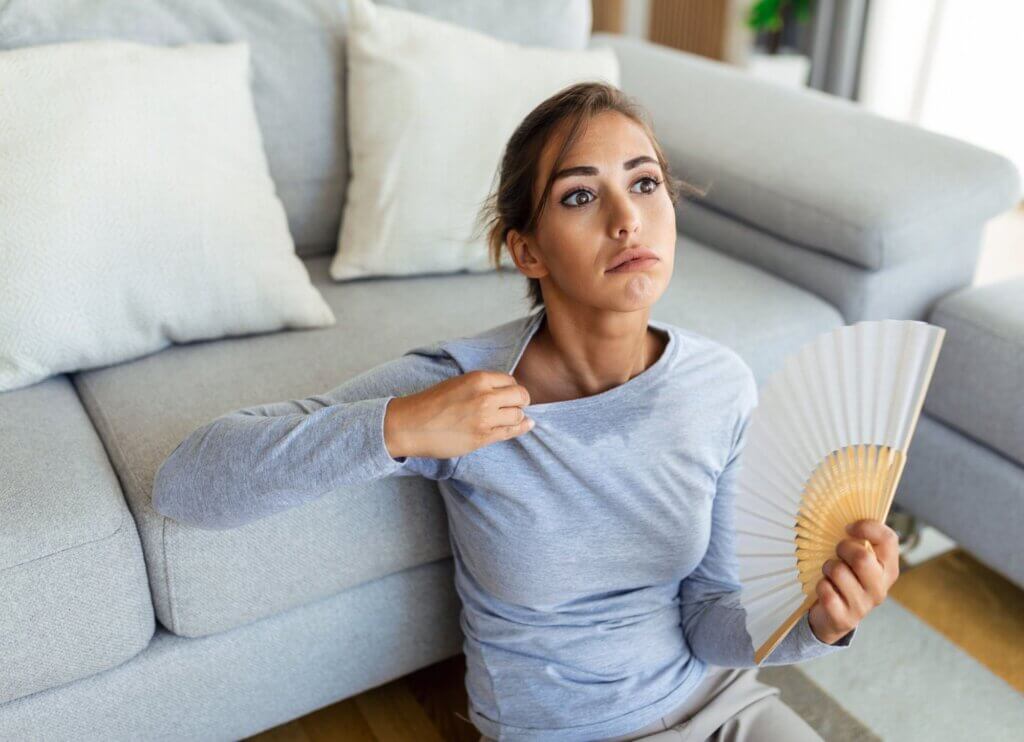 A woman fanning herself in a hot living room